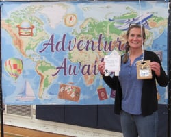 Smiling woman holding gift package in front of banner showing a map of the world. Smiling woman holding gift package in front of banner showing a map of the world.