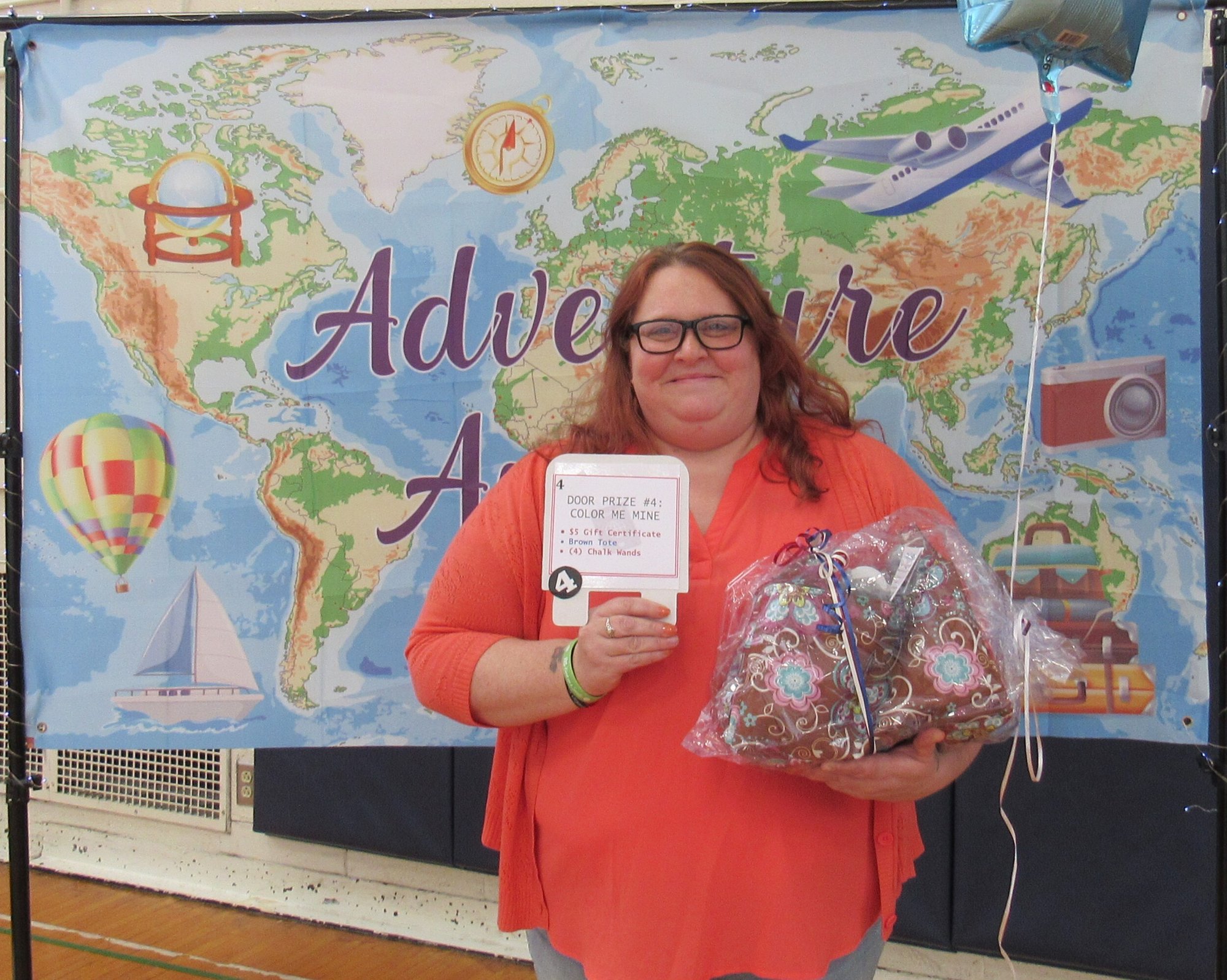 Smiling woman holding gift package in front of banner showing a map of the world. Smiling woman holding gift package in front of banner showing a map of the world.