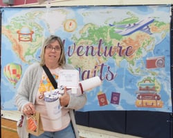 Smiling woman holding gift package in front of banner showing a map of the world. Smiling woman holding gift package in front of banner showing a map of the world.