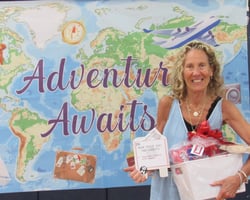Smiling woman holding gift package in front of banner showing a map of the world. Smiling woman holding gift package in front of banner showing a map of the world.