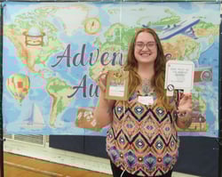 Smiling woman holding gift package in front of banner showing a map of the world.