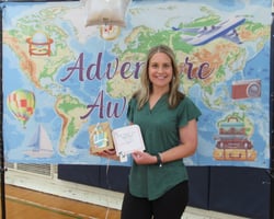 Smiling woman holding gift package in front of banner showing a map of the world. Smiling woman holding gift package in front of banner showing a map of the world.