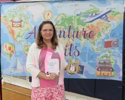 Smiling woman holding gift package in front of banner showing a map of the world. Smiling woman holding gift package in front of banner showing a map of the world.