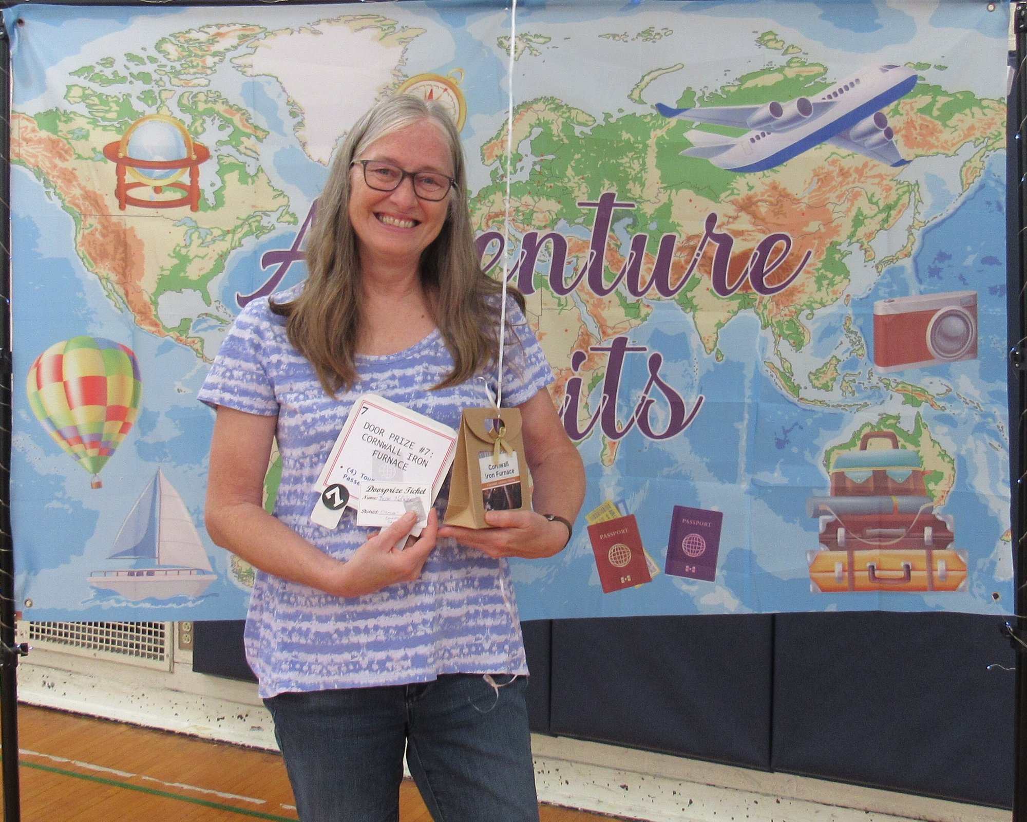 Smiling woman holding gift package in front of banner showing a map of the world. Smiling woman holding gift package in front of banner showing a map of the world.