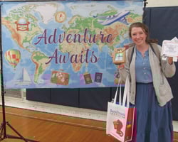 Smiling woman holding gift package in front of banner showing a map of the world. Smiling woman holding gift package in front of banner showing a map of the world.