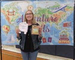 Smiling woman holding gift package in front of banner showing a map of the world. Smiling woman holding gift package in front of banner showing a map of the world.