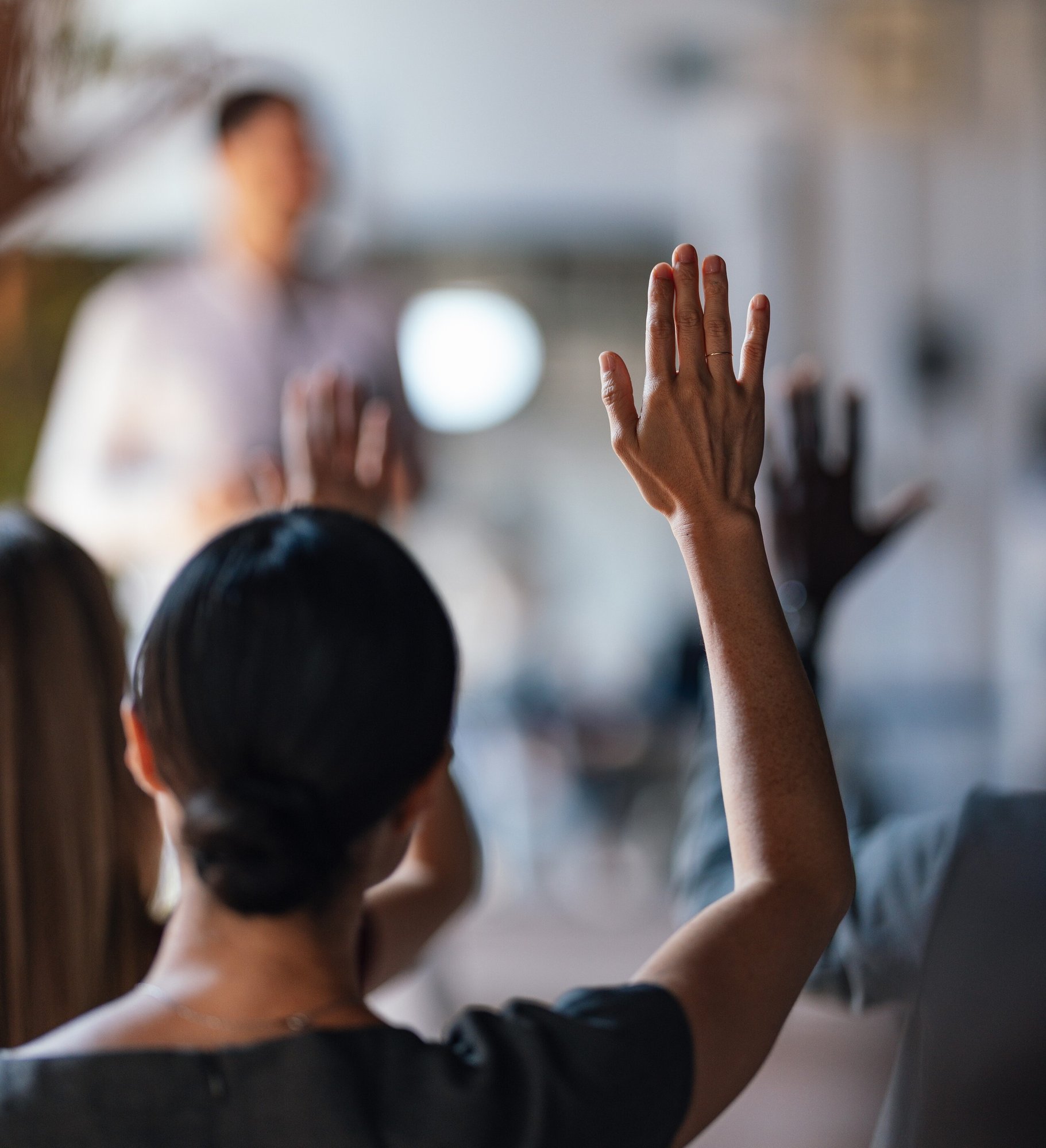 Woman raising her hand at a conference Woman raising her hand at a conference